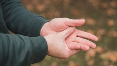 hombre masajeando sus manos por calambres / hormigueo en las manos - 8 consejos para reducir el dolor en las articulaciones de las manos - síntomas de la artritis que incluso podrías pasar por alto / potasio / pelo en las palmas de las manos