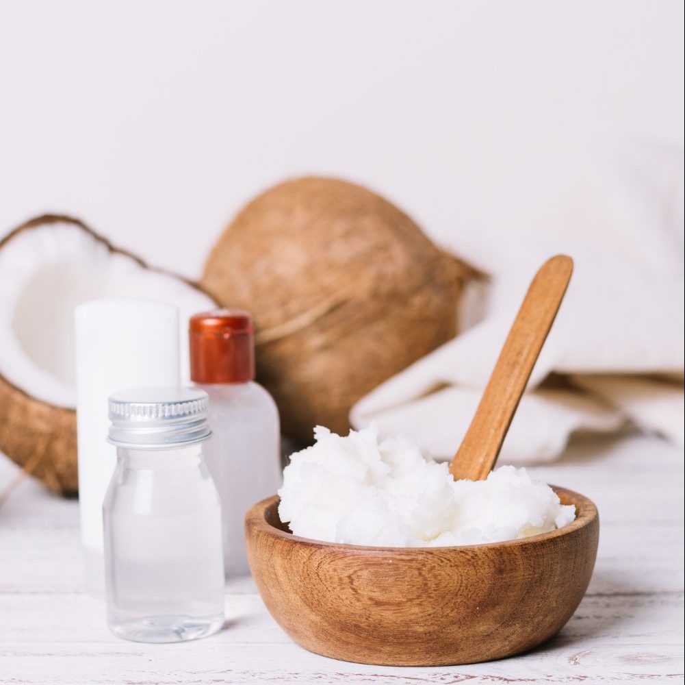 Foto de aceite de coco en frasco de vidrio, con cocos alrededor