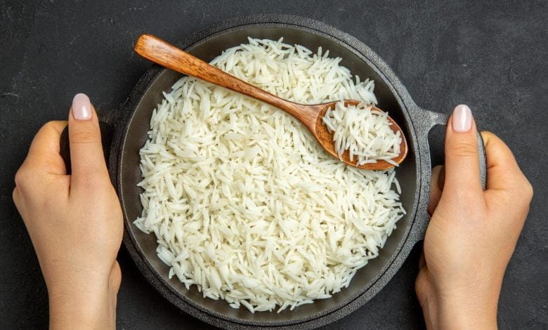 arroz cocido dentro de la sartén en la superficie oscura - arroz todos los días